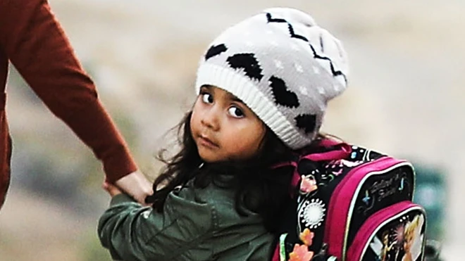 Niña tomada de la mano con su madre en la frontera de México.