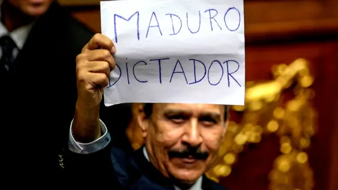 Один из конгрессменов во время голосования на экстренной сессии парламента поднял над головой листок со словами "Мадуро - диктатор"