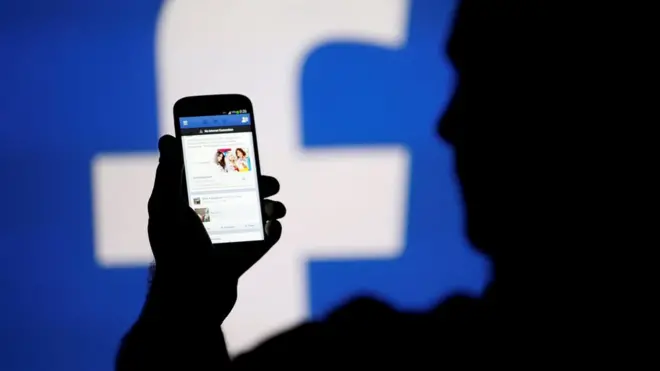 Telefon ekranında Facebook'a bakan bir kişi