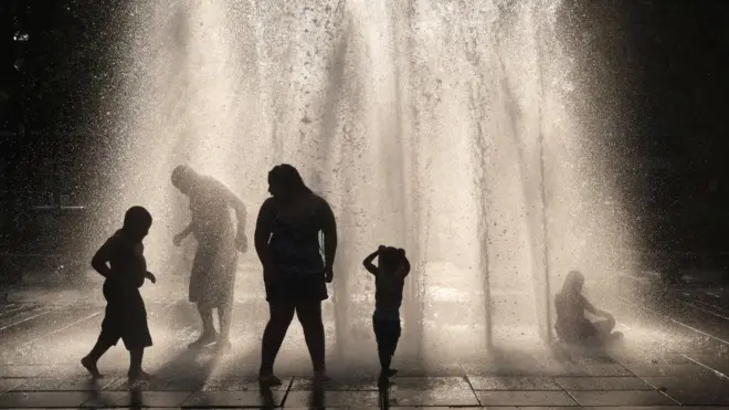 Gente refrescándose en una fuente