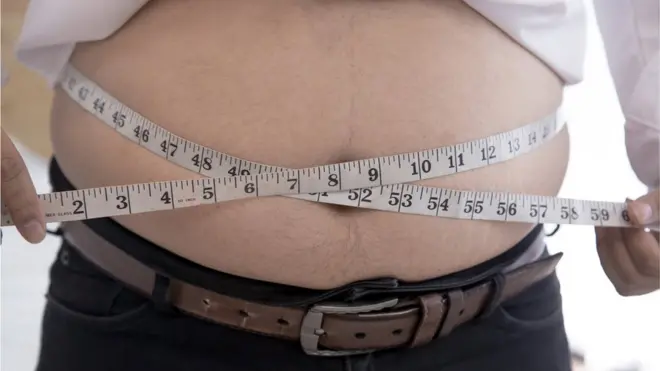 Man measuring his waist with a tape measure