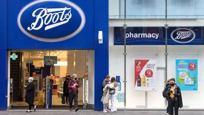 Shoppers pass by a Boots pharmacy in London.