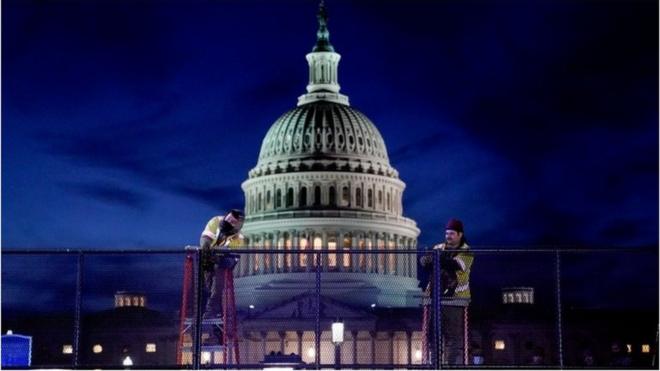 Builders erect a fence around the US Capitol after a mob occupied the building