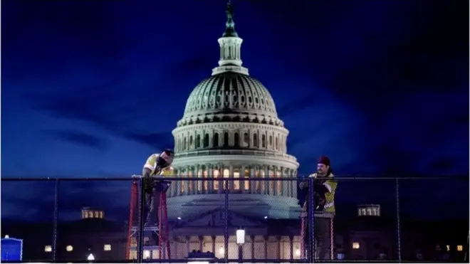 Builders erect a fence around the US Capitol after a mob occupied the building