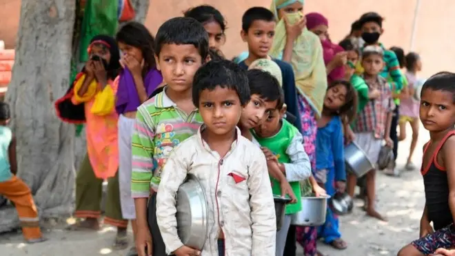 Anak-anak yang tinggal di kawasan kumuh di New Delhi, India, sedang antri untuk mendapatkan sumbangan makanan, 15 Juni 2020.