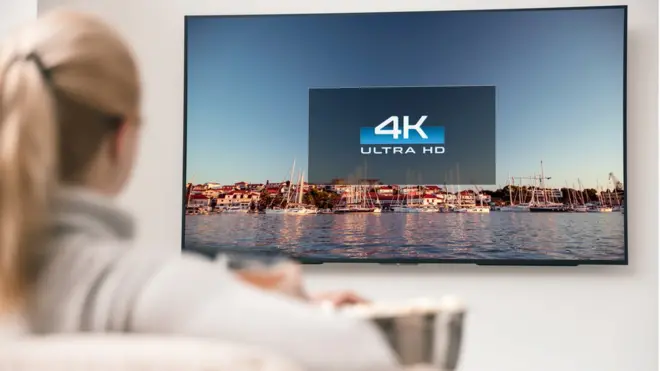 Mujer viendo un televisor en 4K.