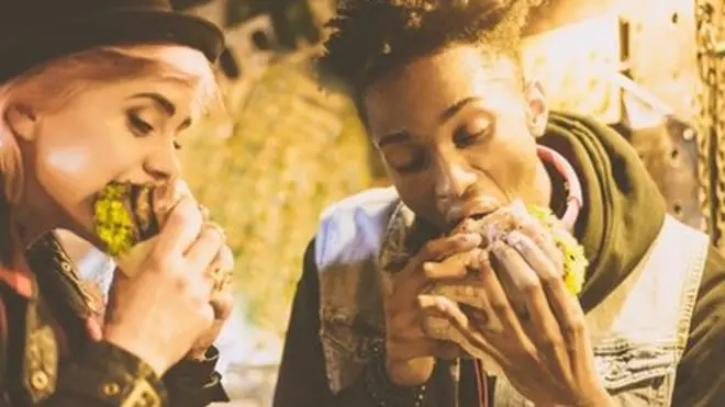 اثنان يأكلان البرغر الغني بالدهون