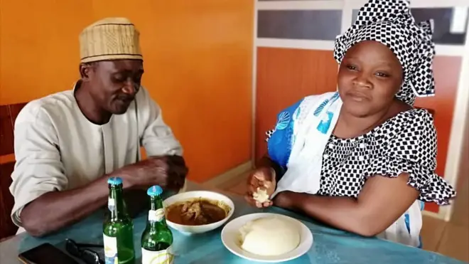 Des clients d'un restaurant en train de déguster un plat de "pâte" fait à base de farine d'ignames séchées.