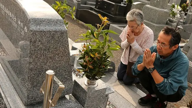 Una mujer y un hombre en Japón realizan una ceremonia para honrar a sus antepasados.