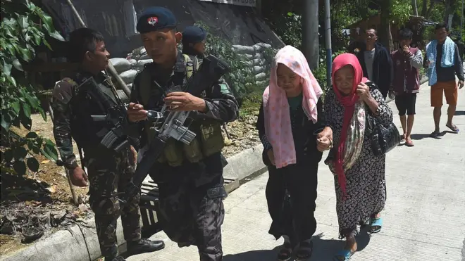 Polisi Filipina membantu warga sipil untuk keluar dari Marawi yang menjadi ajang pertempuran sengit antara tentara dengan milisi Maute pro ISIS.