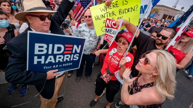 Seorang pendukung capres Joe Biden berada di tengah kerumuan pendukung capres pertahana Donald Trump di depan kantor komisi pemilihan umum di Maricopa County, Phoenix, Arizona, 6 November 2020.