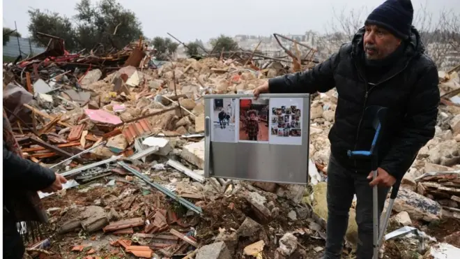 رجل يقف بين حطام منزل العائلة المهدم