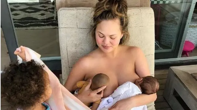 Chrissy Teigen menyusui anaknya dan boneka putrinya.
