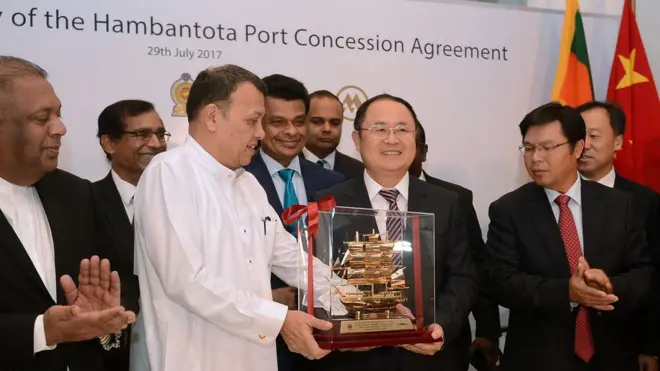 Lễ nhượng cảng: Bộ trưởng Mahinda Samarasing nhận quà từ ông Hồ Kiến Hoa, Phó Chủ tịch CMPH, tập đoàn quản lý cảng thương mại Trung Quốc trong lễ nhượng cảng Hambantota hôm 29/07/2017 cho phía Trung Quốc