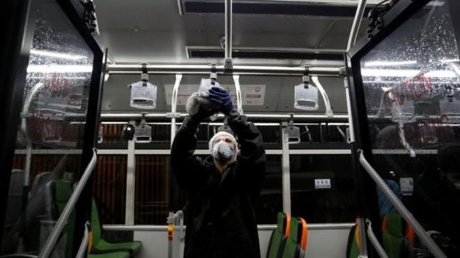 um funcionário limpa uma das alças de apoio em um ônibus no Irã