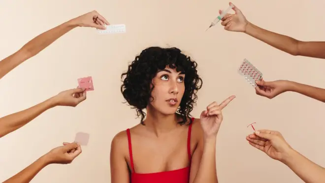 Mujer señala las pastillas anticonceptivas de entre muchas manos ofreciendo diversos métodos anticonceptivos