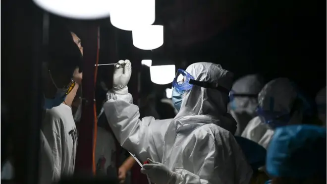 A medical worker collects swab from a resident for nucleic acid testing at dawn