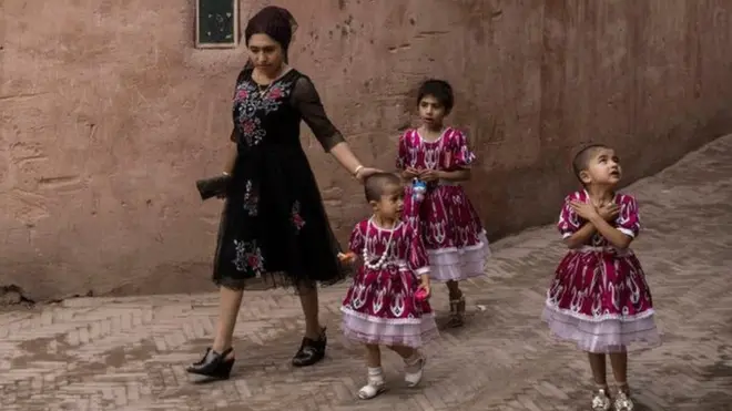An ethnic Uyghur woman walks with her children on June 28, 2017 in the old town of Kashgar, in the far western Xinjiang province, China.