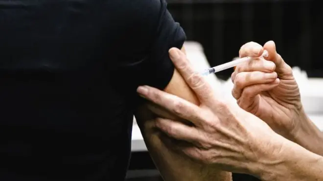 Las manos de una enfermera inyectando el brazo de una paciente