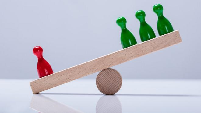 Pequena gangorraroletas personalizadasmadeira pende para o lado com um pino vermelho, mais pesado que aqueles no outro lado, com três pinos verdes