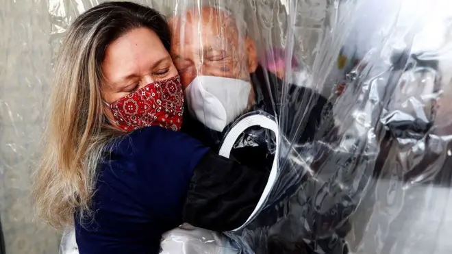 У бразильському Сан-Паулу жінка обіймає свого 82-річного батька крізь "завісу для обіймів"