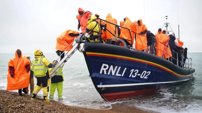 People wearing bright protective clothing alighting a rescue boat on a beach