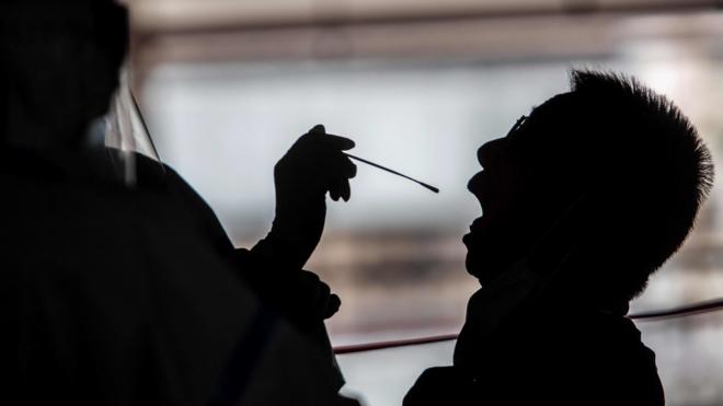 香港某政府停车场大楼内一名医护人员在临时新冠病毒检测采样站给一名出租车司机采集样本（19/7/2020）