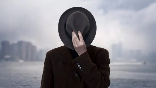 Мужчина прикрывает лицо шляпой