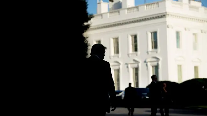 Donald Trump silhouetted against the White House