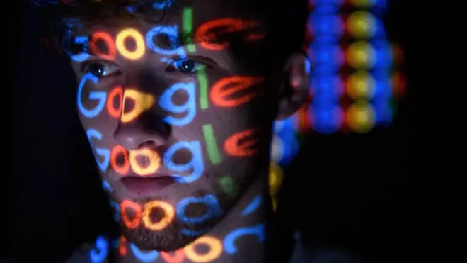 Joven con el logo de Google reflejado en la cara.