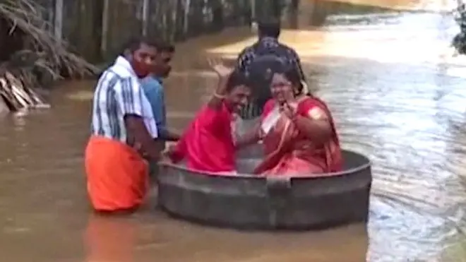 A couple travel to their wedding venue in a large cooking pot, Thalavady, Kerala state