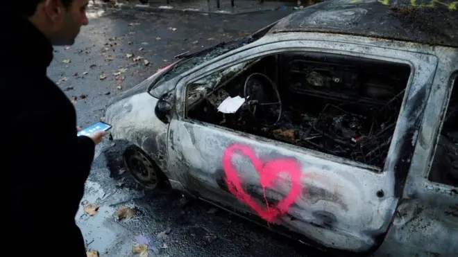 Seorang pria melongok sebuah mobil yang terbakar di Paris, 2 Desember 2018, sehari setelah kerusuhan anti pemerintah melanda kota itu.