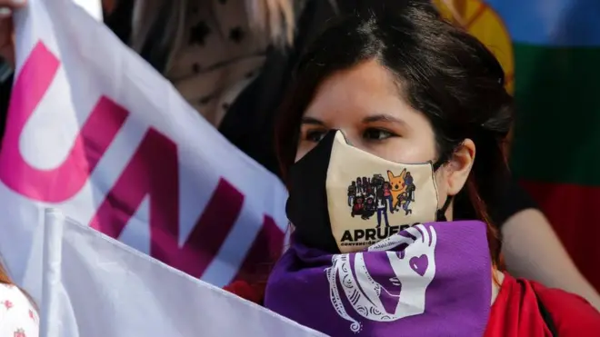 A woman wearing a face mask takes part in a protests in Santiago demanding a new constitution, 18 October 2020