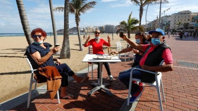 Italian tourists celebrate being able to sit on a terrace at promenade of Las Canteras beach