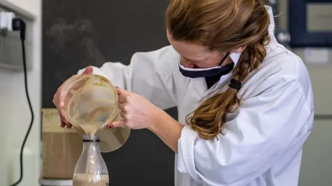 Woman pouring mixture into a bottle