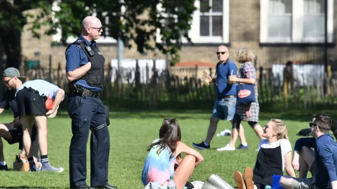 Police speak to people gathering in a park in England