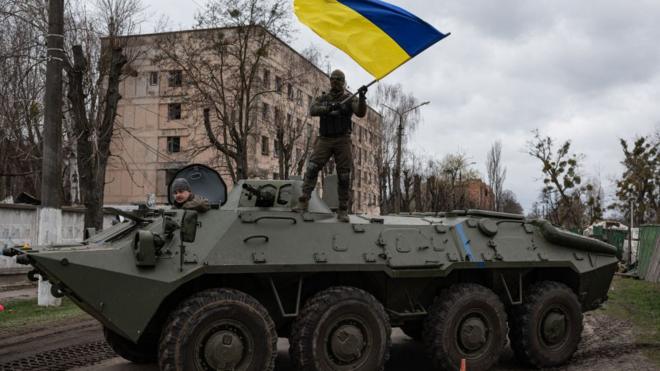 Ukrainian soldier waves Ukrainian national flag while standing on top of an armoured personnel carrier (APC) on April 8, 2022 in Hostomel, Ukraine.