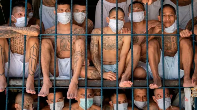 Tattooed male prisoners packed together behind bars in El Salvador