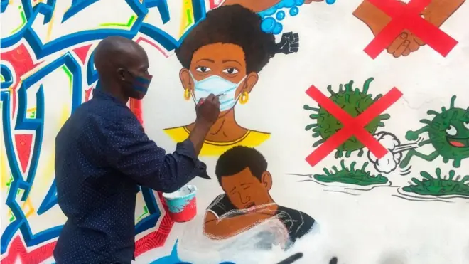 L'artiste congolais Chris Shongo peint une fresque sur le thème du coronavirus sur le mur extérieur de l'Académie des Beaux-Arts à Kinshasa, en juin 2020