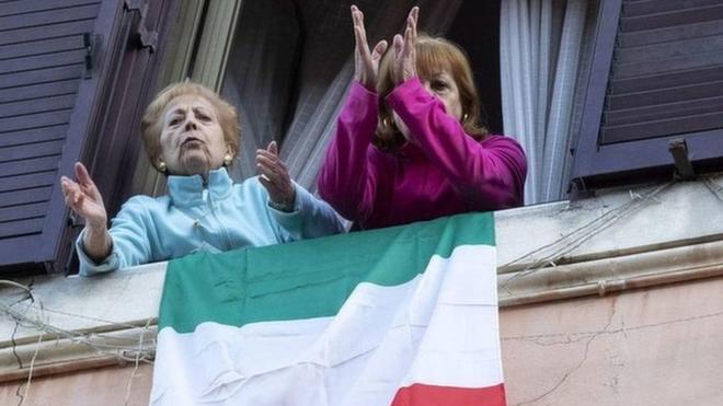 Two women look out of the window before singing during a flash mob in Rome, Italy, 16 March 2020.