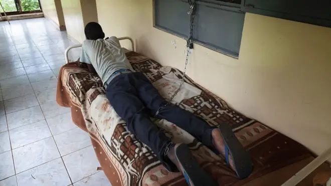 Pyschia patient wey dem chain on top bed.