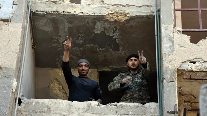 Syrian soldiers making a V for victory sign from a window of damaged building in Aleppo's eastern Masaken Hanano area in Aleppo province, Syria, 27 November