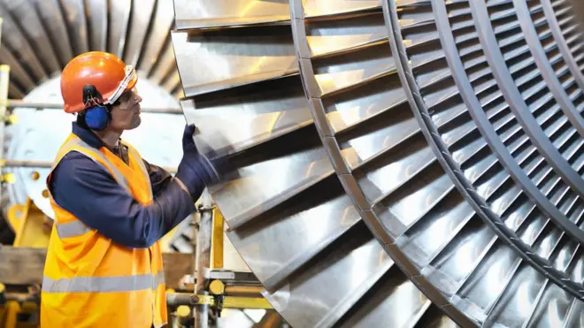 Un ouvrier inspecte une turbine dans une centrale électrique.