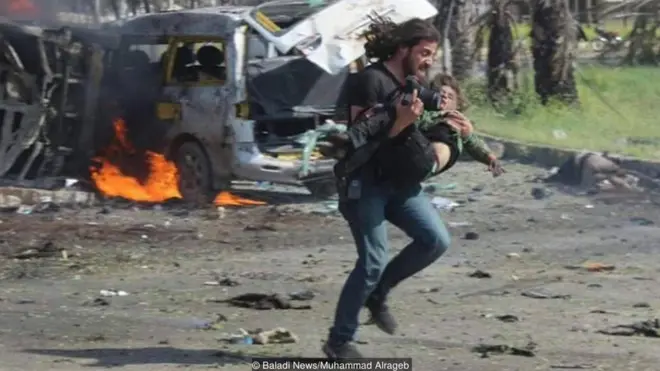 Phóng viên ảnh người Syria Abd Alkader Habak bế một em nhỏ tới nơi an toàn sau khi đoàn xe buýt chở những người dân đi sơ tán khỏi các ngôi làng Syria bị đánh bom