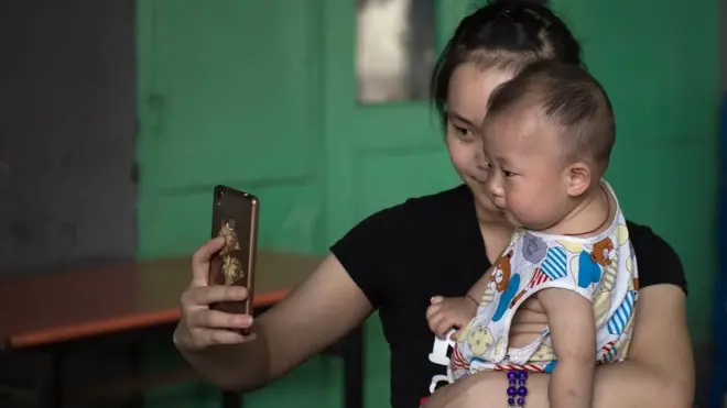 A woman takes a selfie with a baby on a street in Beijing