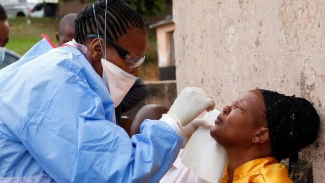 A health worker wearing a protective suit takes a swab from a resident during a door-to-door testing
