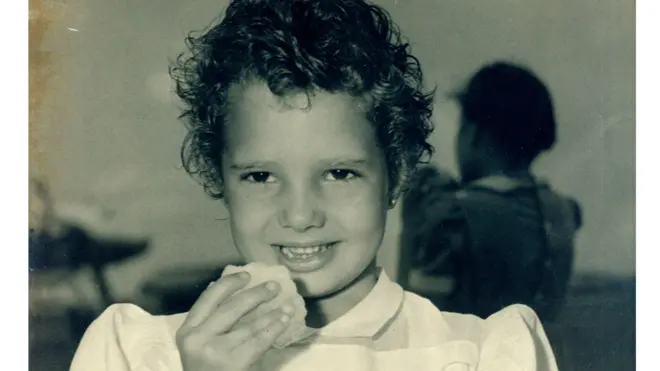 Niña sostiene una bola de nieve en sus manos