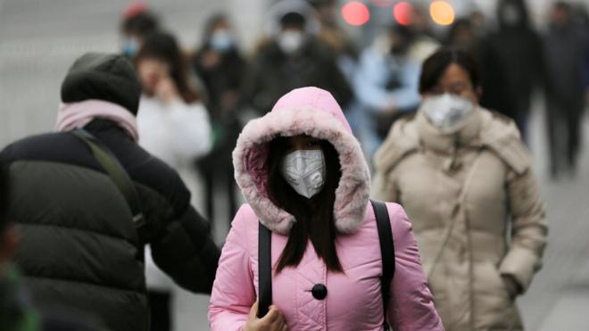 12月21日，北京街頭，一處辦公區域附近戴口罩的行人。