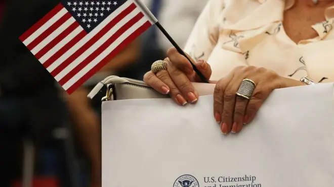 Pesin hold American flag during one ceremony to become an American citizen during one US Citizenship and Immigration Services naturalization ceremony for Miami.