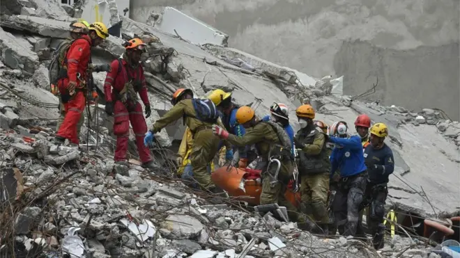 Regu penyelamat mengusung korban gempa dari sebuah gedung yang ambruk di Mexico City.